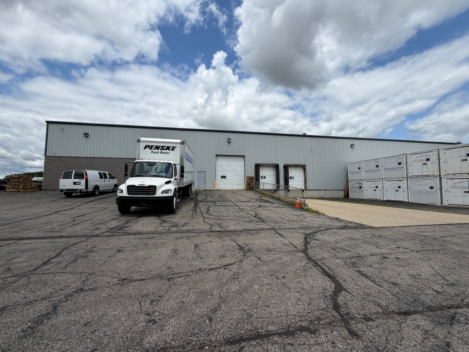 Penske box truck backed up to the warehouse loading dock alongside MobiStor containers